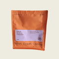 An orange stand-up pouch of West Coast Cocoa Deluxe Drinking Chocolate, 250g, on a light beige background.