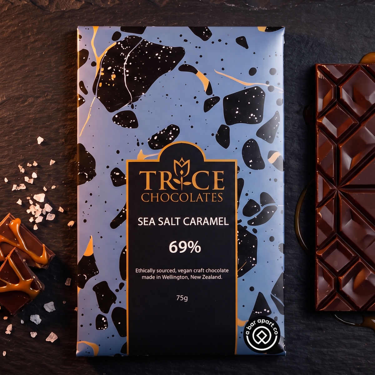 Sea salt caramel dark chocolate bar in Trice Chocolates packaging with chocolate pieces, caramel and sea salt.