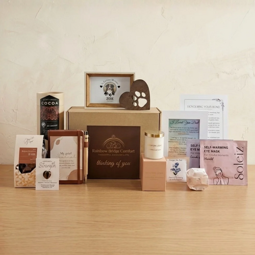 Complete Comfort pet sympathy gift box by Rainbow Bridge Comfort, featuring a curated collection of grief support items. Includes personalised dog memorial photo frame, metal heart paw ornament, journal with pen, luxury candle, self-warming eye masks, West Coast Cocoa, gourmet chocolate bark, Forget-Me-Not seeds, and a tiger's eye pocket stone.