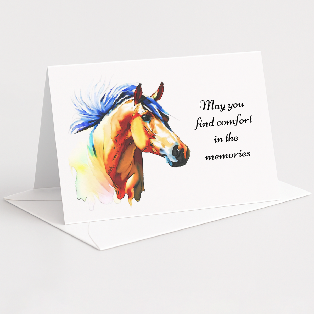 A white standing greeting card with a colorful watercolor illustration of a horse and the printed message 'May you find comfort in the memories,' shown on a clean light gray background with an envelope behind it.